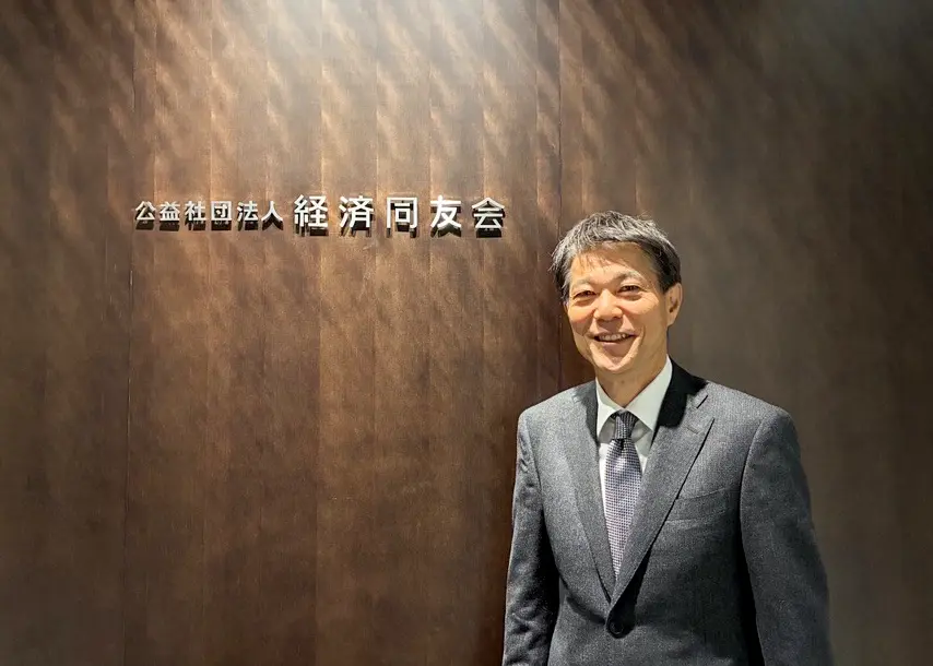 経済同友会の看板の前に立つ日色 保さん
